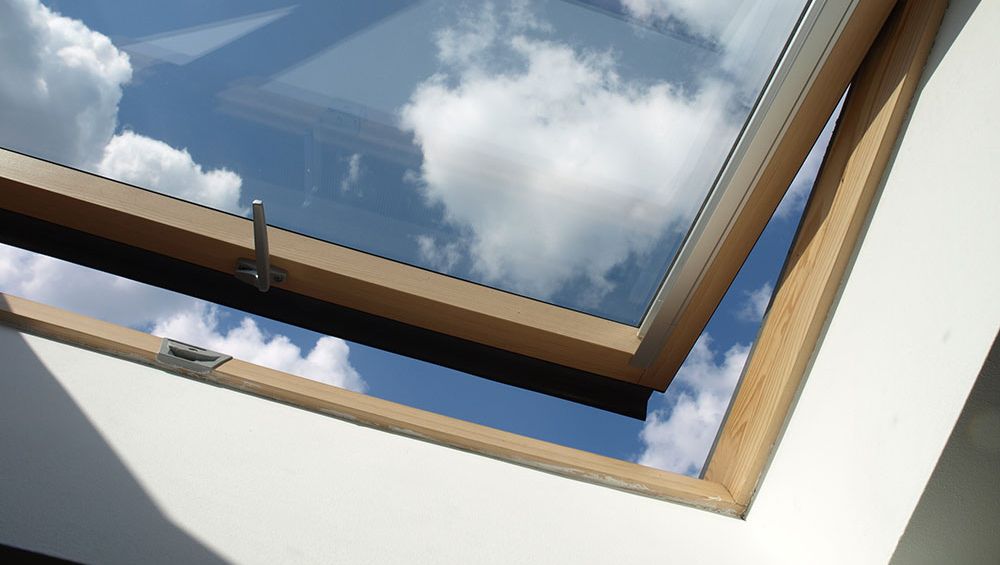 Dachfenster mit Holzrahmen und Ausblick auf den blauen Himmel